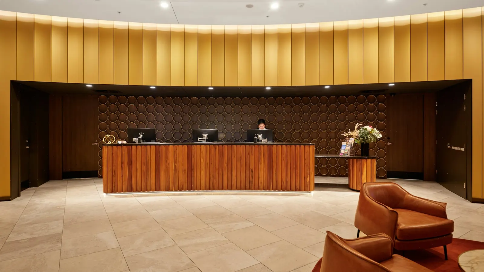 Recepção de hotel vazia, com balcão de madeira e iluminação quente